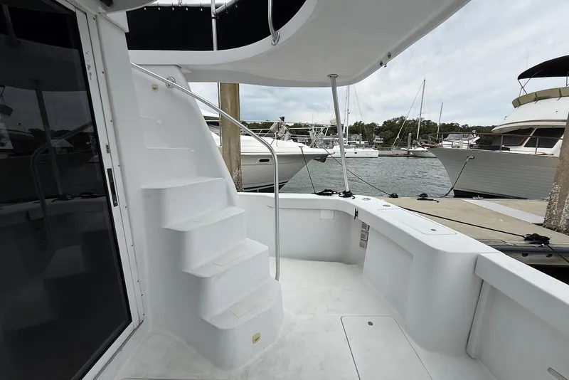 Slide: The Image of 1998 Mainship 350 Trawler deck with stairs, docked at marina with boats in background. - 17
