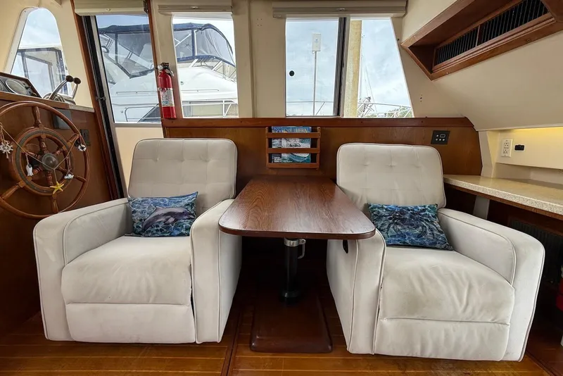Slide: The Image of Interior of a 1998 Mainship 350 Trawler with white armchairs and wooden table. - 20