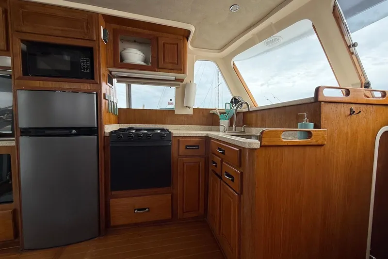Slide: The Image of 1998 Mainship 350 Trawler kitchen with wood cabinetry, stove, and stainless steel appliances. - 21