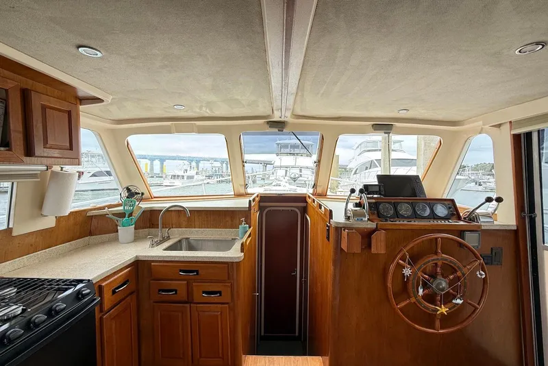 Slide: The Image of Interior of 1998 Mainship 350 Trawler with helm, kitchen, and marina view. - 25