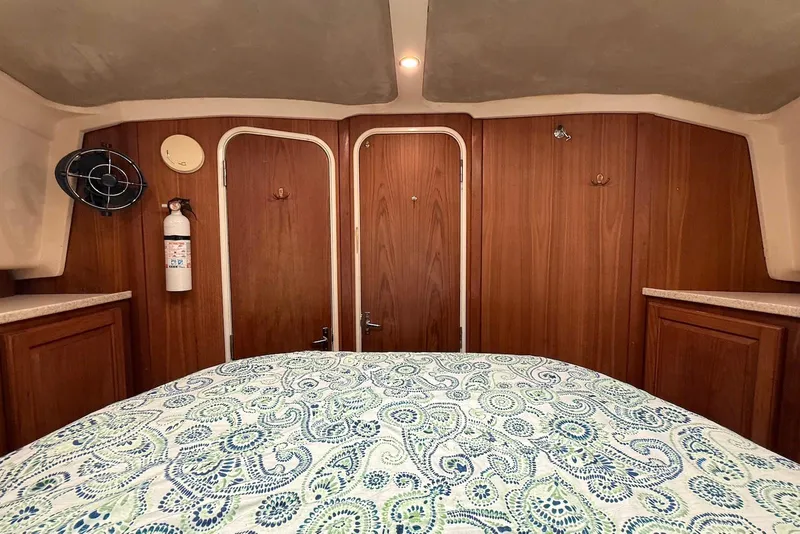 Slide: The Image of Interior cabin of 1998 Mainship 350 Trawler with wood paneling and patterned bedding. - 30