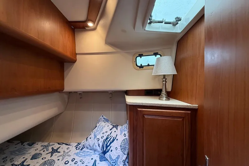Slide: The Image of Cozy cabin interior of 1998 Mainship 350 Trawler with nautical-themed bedding and wooden cabinetry. - 31