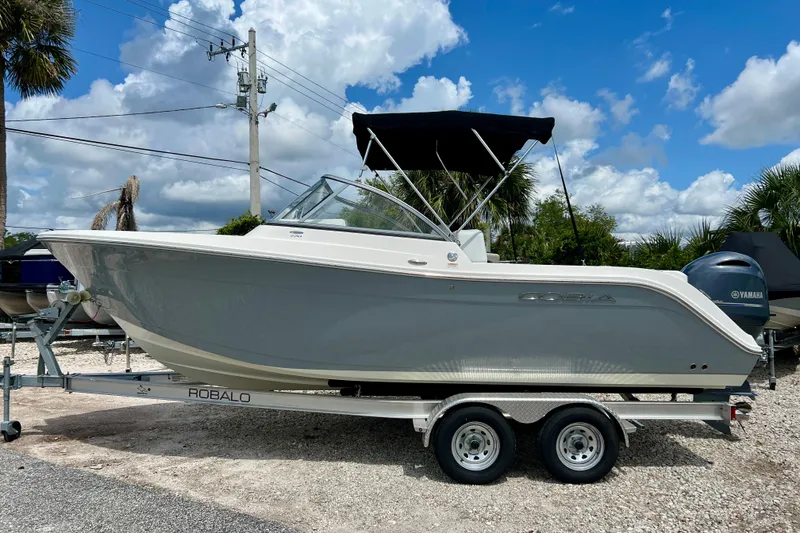 The Image of 2023 Cobia 220 Dual Console boat on trailer under blue sky. - 1