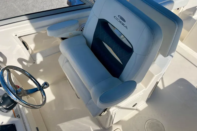 Slide: The Image of 2023 Cobia 220 Dual Console boat interior with steering wheel and cushioned seat. - 11