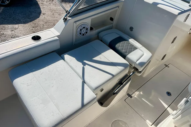Slide: The Image of 2023 Cobia 220 Dual Console boat interior with cushioned seating and speaker. - 13