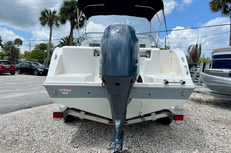 Slide: The Image of 2023 Cobia 220 Dual Console boat with outboard motor, parked on gravel lot. - 3