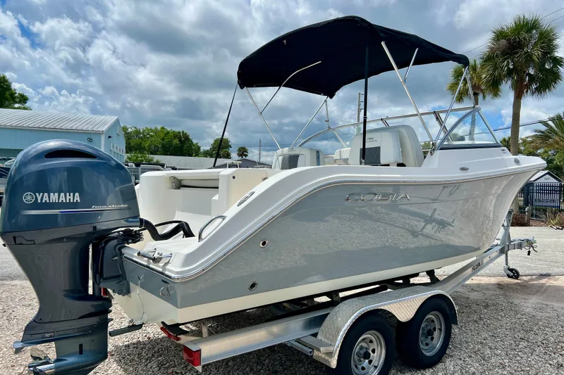 Slide: The Image of 2023 Cobia 220 Dual Console boat with Yamaha engine on trailer, under cloudy sky. - 4