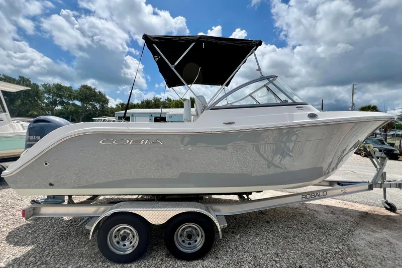 Slide: The Image of 2023 Cobia 220 Dual Console boat on trailer under a cloudy sky. - 5