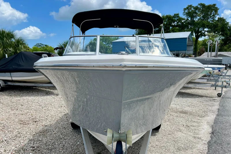 Slide: The Image of 2023 Cobia 220 Dual Console boat with black canopy, parked outdoors on gravel. - 7