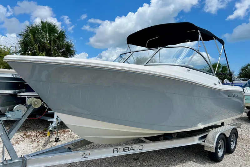 Slide: The Image of 2023 Cobia 220 Dual Console boat on trailer under blue sky. - 8
