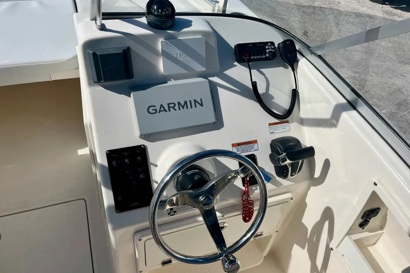 Slide: The Image of 2023 Cobia 220 Dual Console boat dashboard with Garmin navigation system and steering wheel. - 9