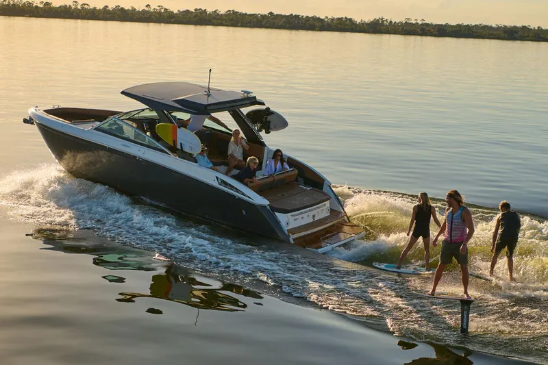 Slide: The Image of Manufacturer Provided Image: 2025 Cobalt R33 Surf boat with people wakeboarding on a calm lake. - 21
