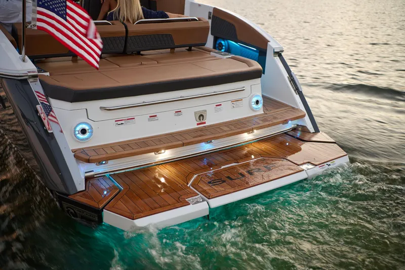 Slide: The Image of Manufacturer Provided Image: 2025 Cobalt R33 Surf boat with American flag, illuminated deck, and teak flooring on water. - 24