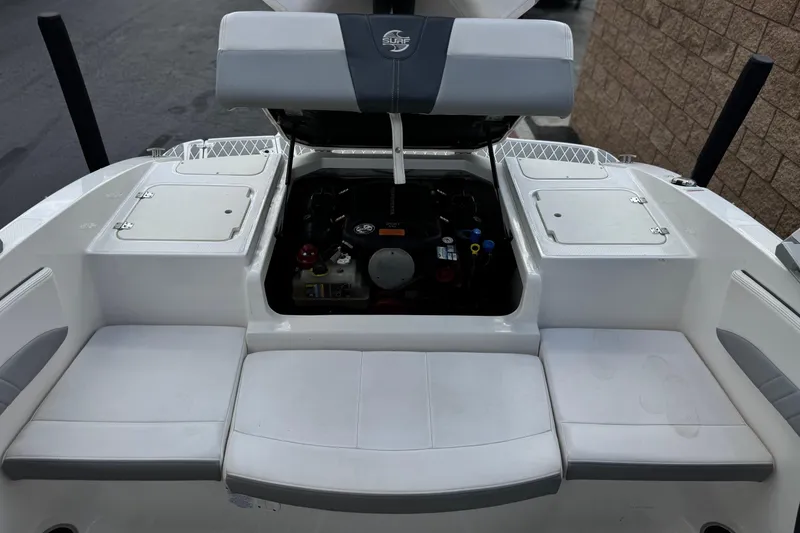 Slide: The Image of 2020 Chaparral 21 Surf boat engine compartment with open hatch, showcasing seating area. - 21