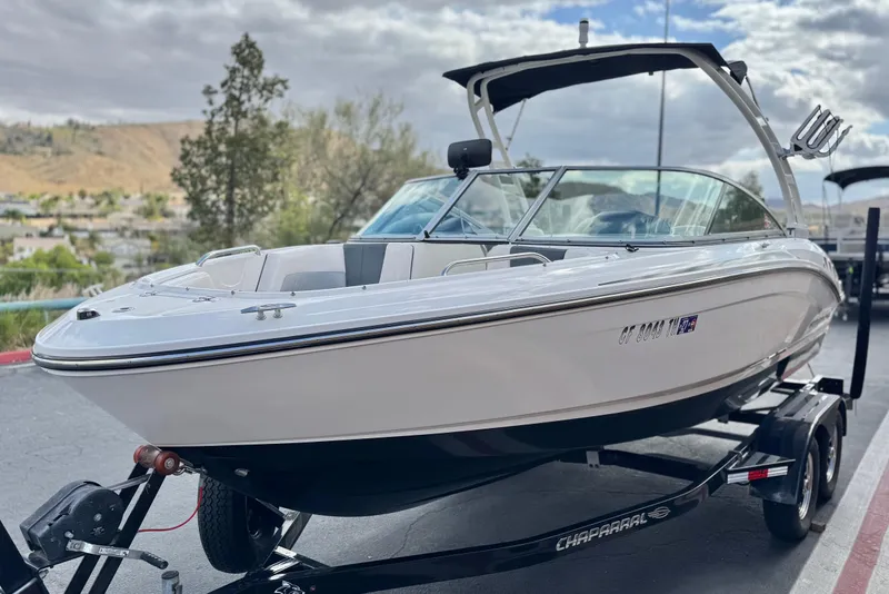 Slide: The Image of 2020 Chaparral 21 Surf boat on trailer, parked outdoors under cloudy sky. - 3