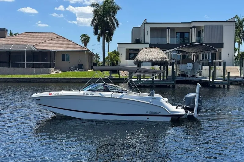 The Image of 2020 Four Winns HD220 OB boat docked on a sunny waterfront with modern homes. - 0