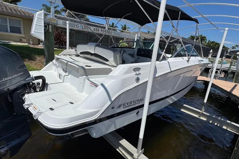 Slide: The Image of 2020 Four Winns HD220 OB boat docked, featuring sleek design and outboard motor. - 11