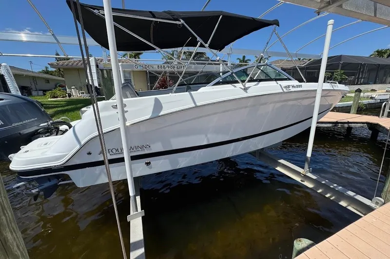 Slide: The Image of 2020 Four Winns HD220 OB boat on lift, featuring sleek design and black canopy. - 12
