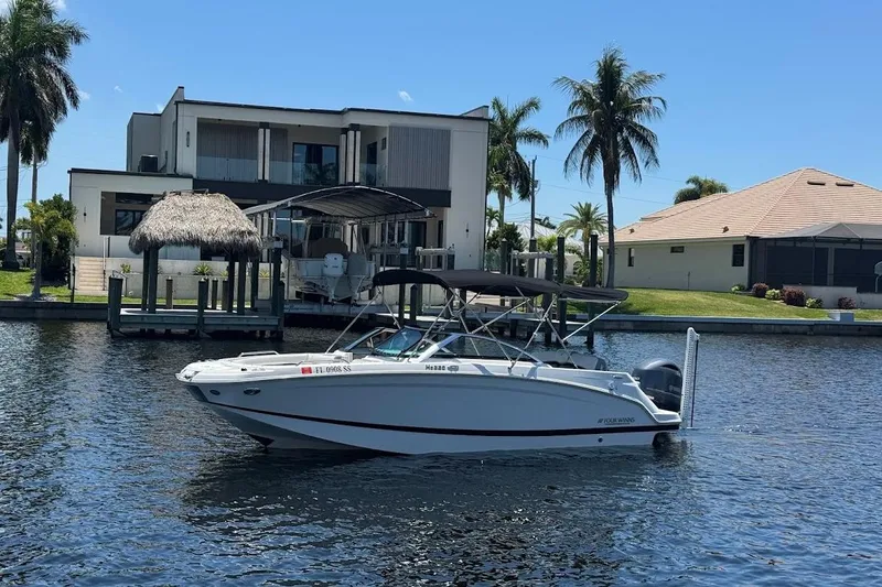 Slide: The Image of 2020 Four Winns HD220 OB boat on water near modern waterfront home with palm trees. - 4