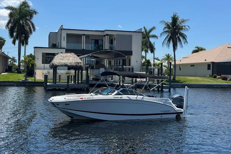 Slide: The Image of 2020 Four Winns HD220 OB boat docked by a waterfront home with palm trees. - 5
