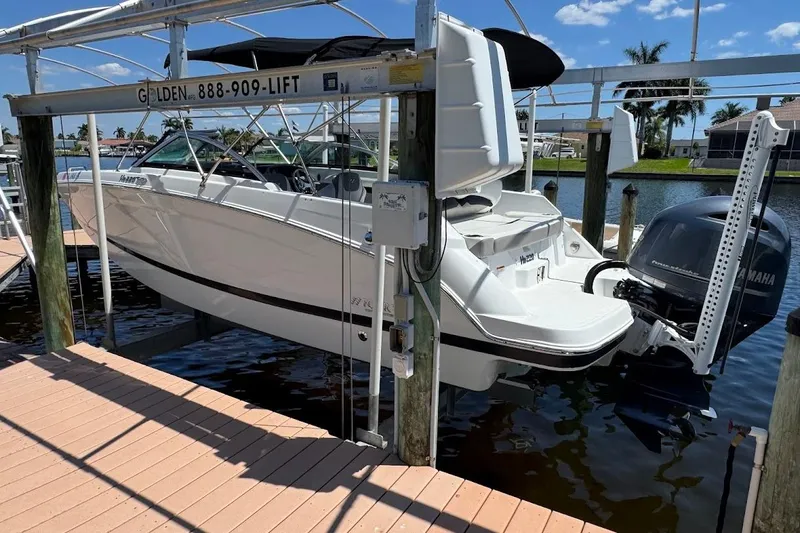 Slide: The Image of 2020 Four Winns HD220 OB boat on lift by dock, sunny day, waterfront view. - 7