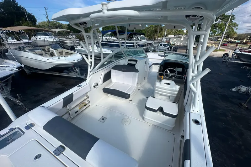 Slide: The Image of 2018 Robalo R247 Dual Console boat interior with seating and helm, docked among other boats. - 21