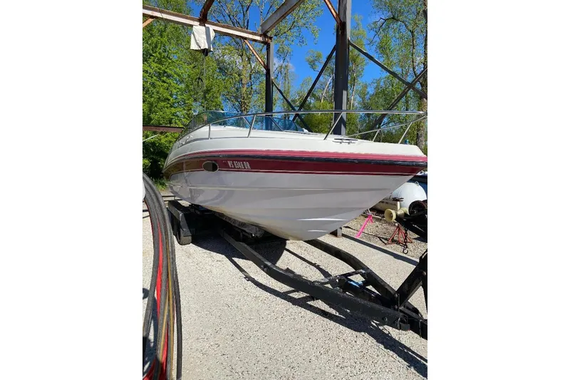 The Image of 1995 Chaparral 2335 SS boat on trailer, surrounded by trees and blue sky. - 1