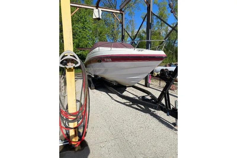 Slide: The Image of 1995 Chaparral 2335 SS boat on trailer, parked outdoors under a metal structure. - 11
