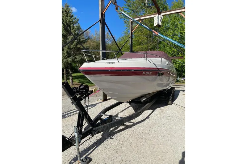 Slide: The Image of 1995 Chaparral 2335 SS boat on trailer, parked outdoors with trees in background. - 12