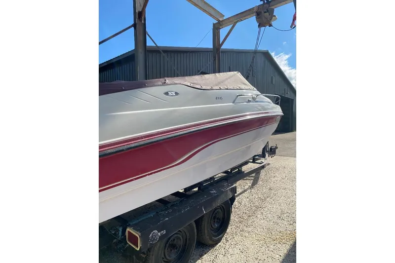 Slide: The Image of 1995 Chaparral 2335 SS boat on trailer, featuring red and white design, parked outdoors. - 14