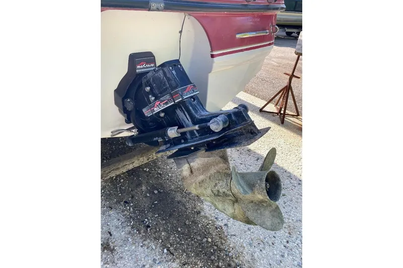 Slide: The Image of 1995 Chaparral 2335 SS boat with MerCruiser outdrive and propeller, parked on gravel. - 6