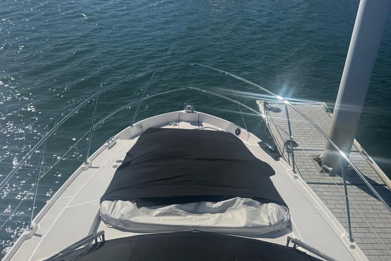Slide: The Image of 2022 Regal 42 FXO yacht docked, featuring a sunpad and sleek design. - 15