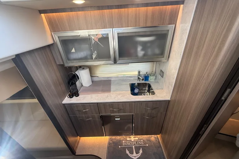 Slide: The Image of Modern galley kitchen in 2022 Regal 42 FXO yacht with wood cabinetry and stainless steel sink. - 33