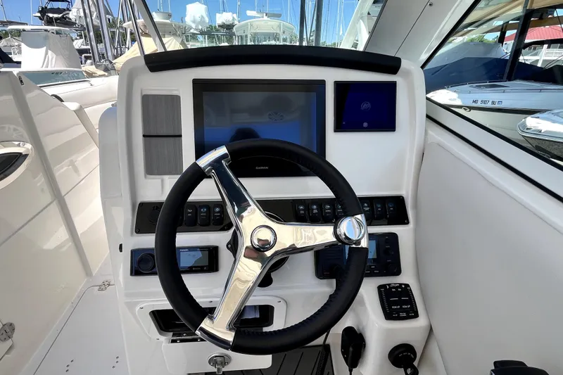 Slide: The Image of 2024 Sailfish 245 DC boat helm with modern steering wheel and navigation controls. - 22