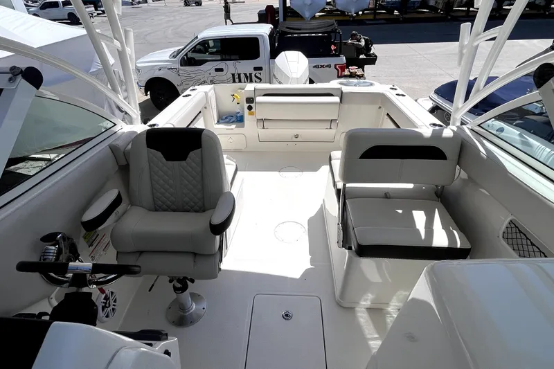 Slide: The Image of 2024 Sailfish 245 DC boat interior with seating and steering wheel, parked near vehicles. - 13