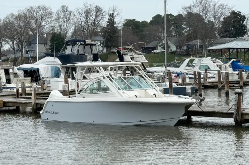 The Image of 2024 Sailfish 245 DC boat docked at a marina with other vessels. - 0