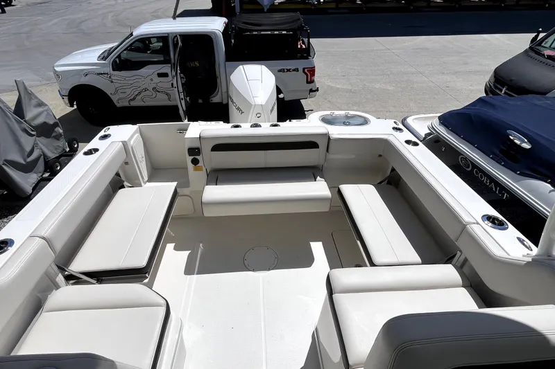 Slide: The Image of 2024 Sailfish 245 DC boat interior with seating, parked near vehicles. - 9