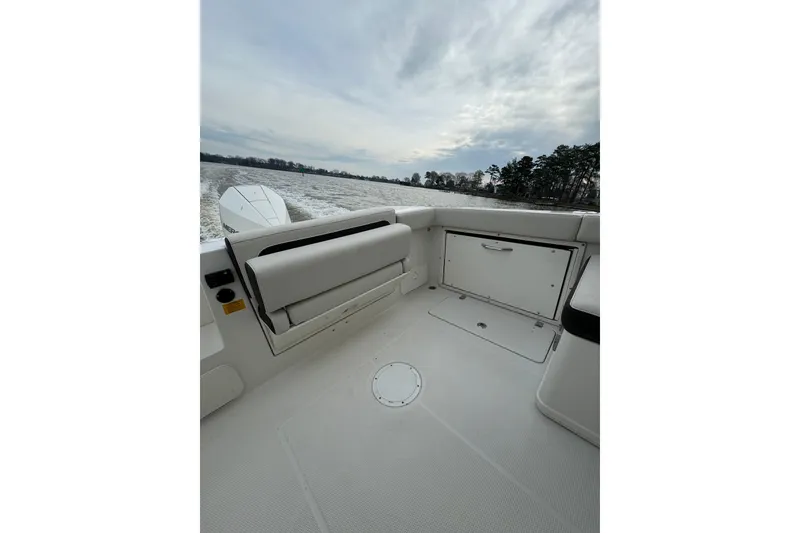 Slide: The Image of 2024 Sailfish 245 DC boat interior with seating and storage, on a calm water backdrop. - 46