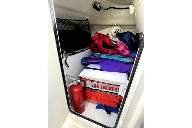 Slide: The Image of Storage compartment in 2024 Sailfish 245 DC boat with life jackets and fire extinguisher. - 25