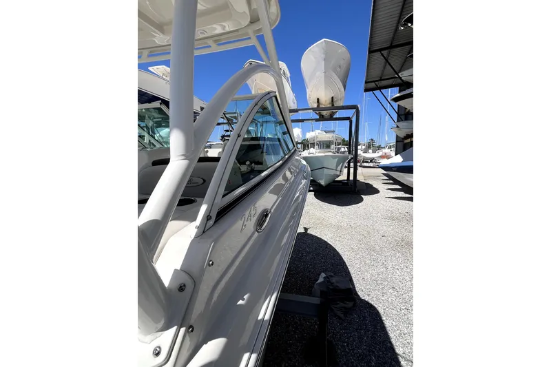Slide: The Image of 2024 Sailfish 245 DC boat in marina, side view under clear blue sky. - 7
