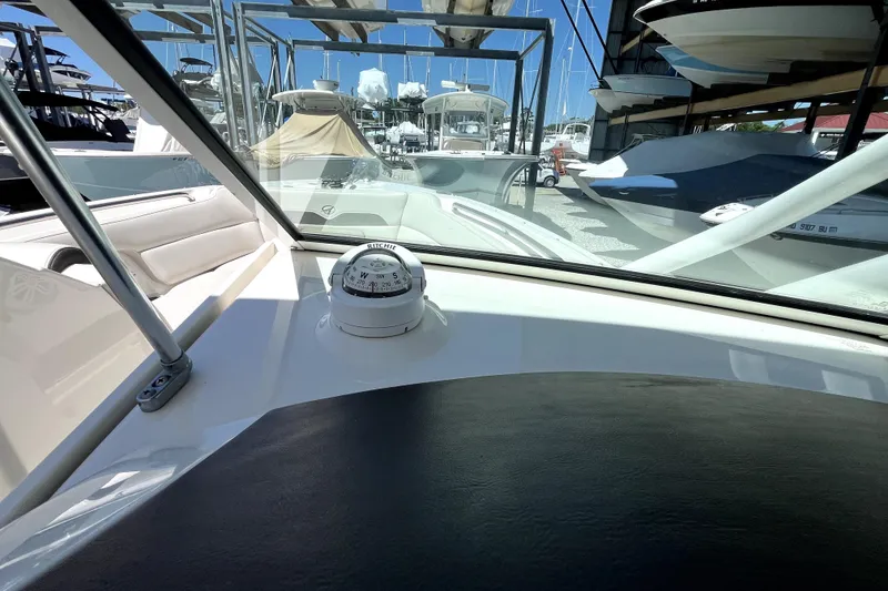 Slide: The Image of 2024 Sailfish 245 DC boat interior with compass, docked among other boats. - 27