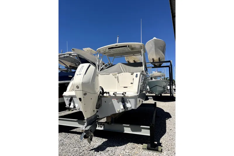 Slide: The Image of 2024 Sailfish 245 DC boat with powerful outboard motor, displayed on a gravel lot. - 6