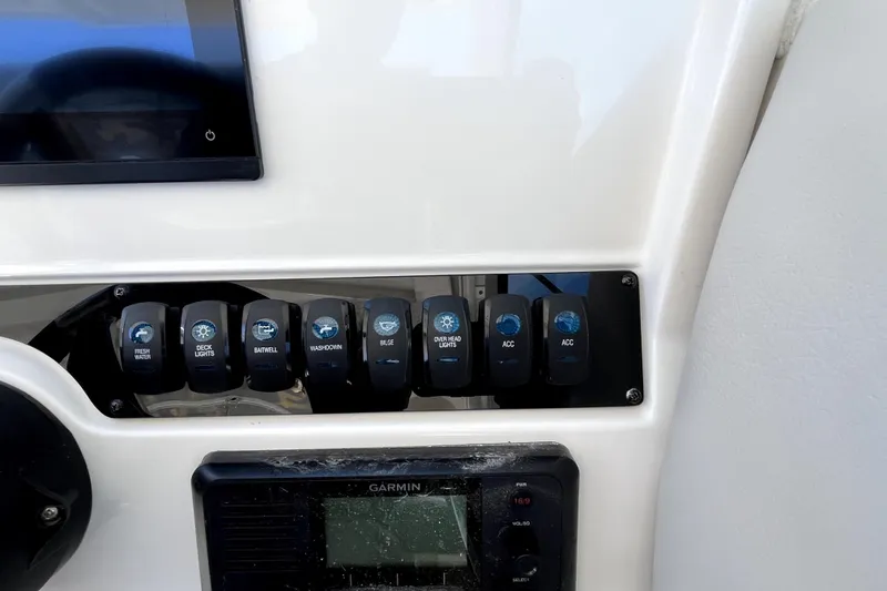 Slide: The Image of Control panel of 2024 Sailfish 245 DC boat with labeled switches and Garmin display. - 24