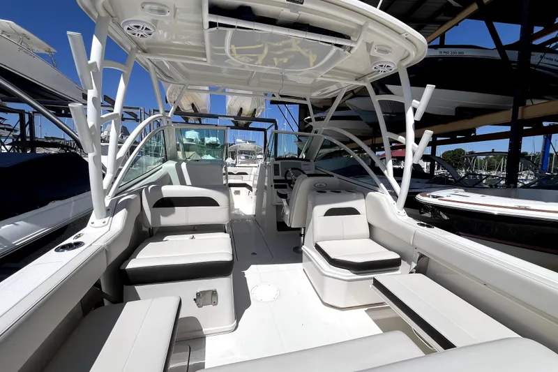Slide: The Image of 2024 Sailfish 245 DC boat interior with seating and canopy in marina setting. - 10