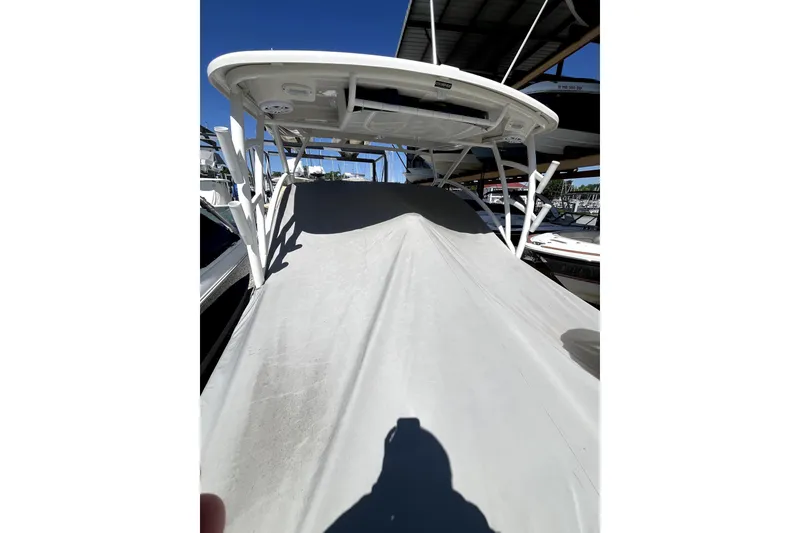 Slide: The Image of 2024 Sailfish 245 DC boat covered, docked under a canopy, sunny day. - 23