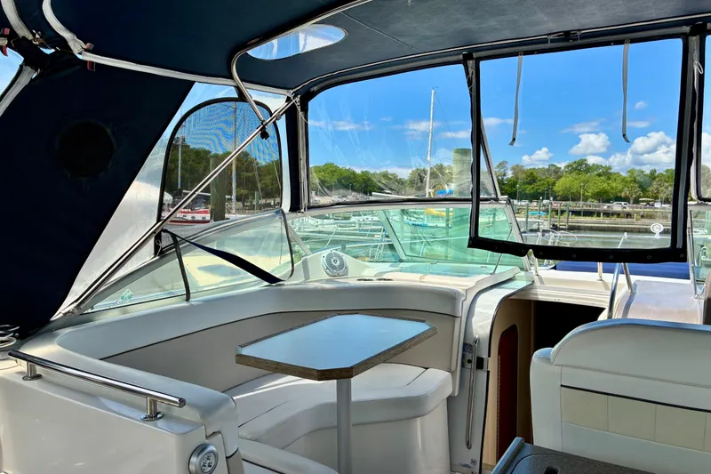 Slide: The Image of 2006 Rinker 390 Express Cruiser interior with marina view, featuring seating and table. - 10