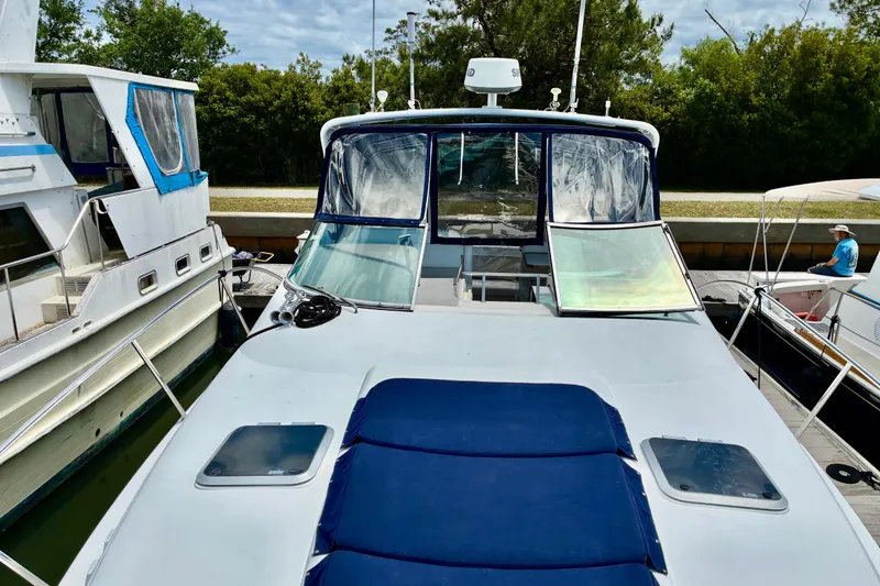 Slide: The Image of 2006 Rinker 390 Express Cruiser docked, featuring blue sun pads and clear cockpit enclosure. - 20