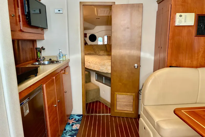 Slide: The Image of 2006 Rinker 390 Express Cruiser interior with kitchenette, seating, and cozy sleeping area. - 23