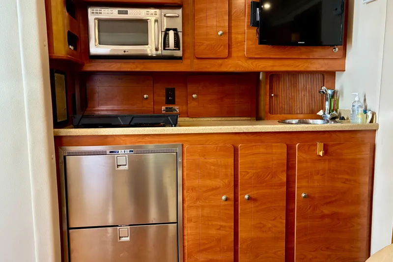 Slide: The Image of 2006 Rinker 390 Express Cruiser kitchen with wood cabinetry, stainless appliances, and modern amenities. - 27