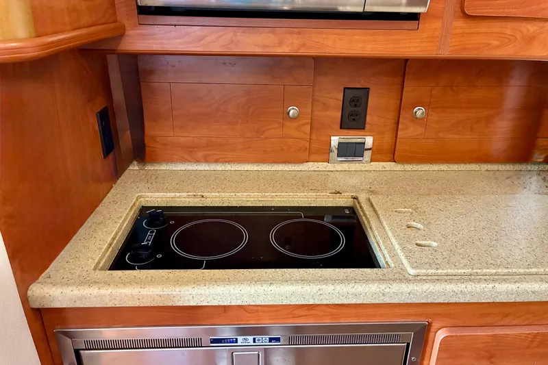 Slide: The Image of 2006 Rinker 390 Express Cruiser kitchen with electric stove and wooden cabinetry. - 28